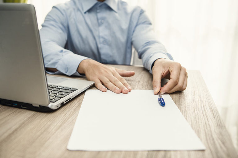 man pushing pen and paper over table