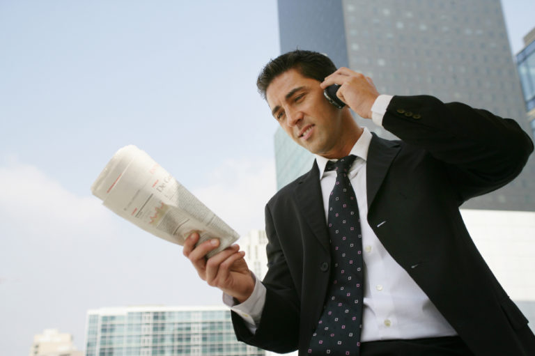 businessman reading newspaper while on the phone