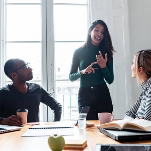 Shot of pretty young entrepreneur woman explaining a project to his colleagues on coworking place.
